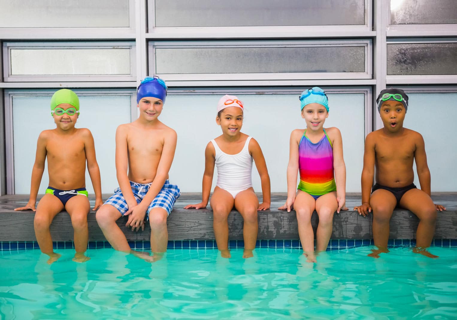 Children sitting by an indoor pool before swim lessons in Nashville, TN.