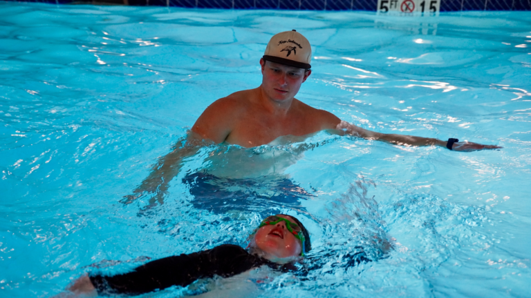 Swimmer practicing a side breath with an instructor at Swim & Play.
